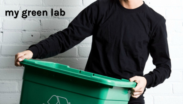 A man in a black shirt holds a green recycling bin